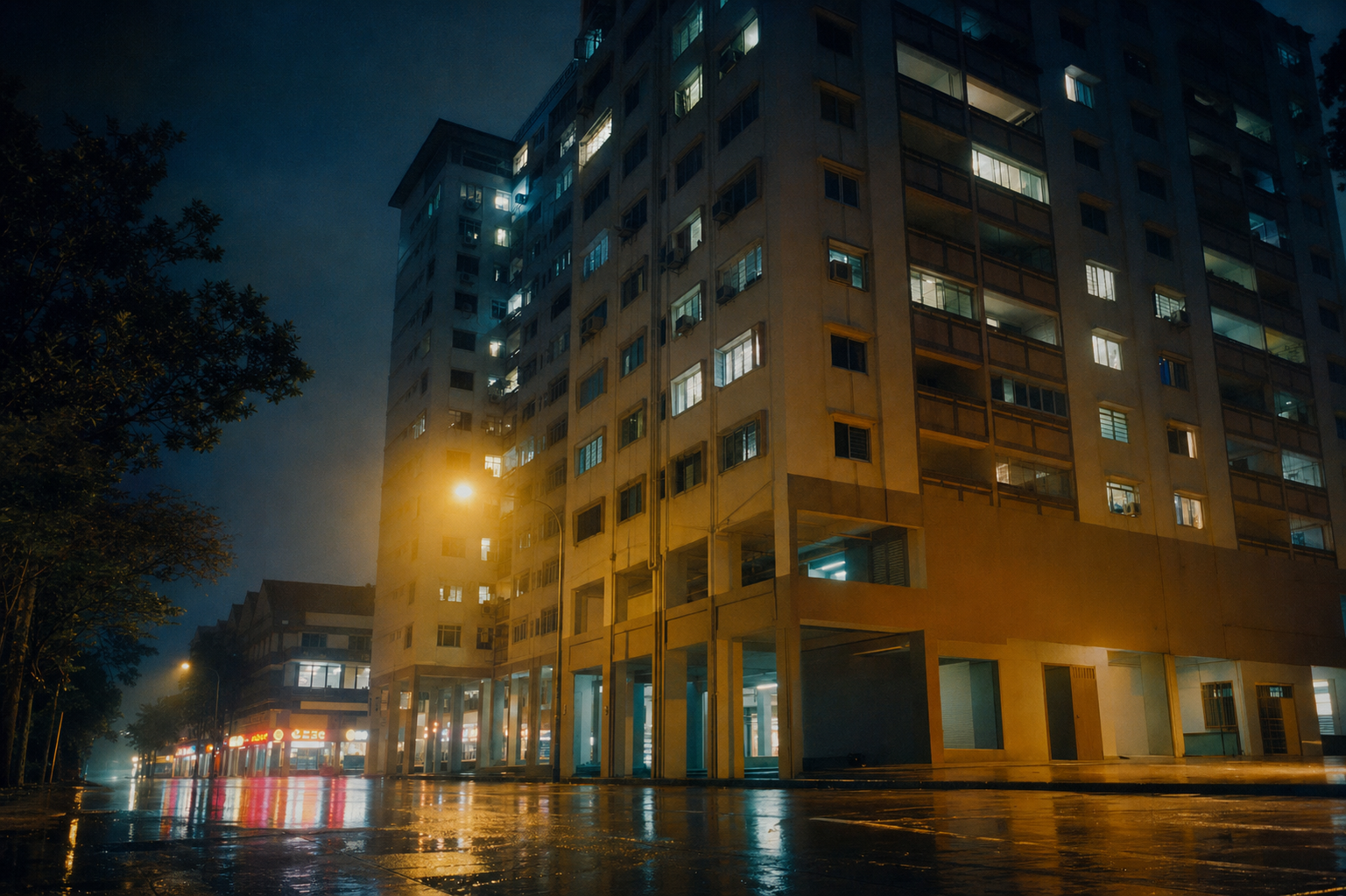 An old high-rise residential block on Chin Swee Road, Singapore, at night. Warm sodium street lights, wet asphalt, quiet street.