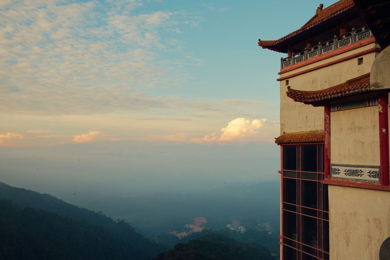why-choose-us A tranquil view from a traditional pagoda overlooking mist-covered mountains at sunset.