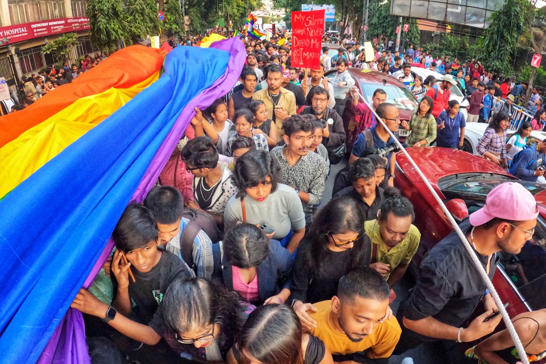 gallery-3 a-large-group-of-people-standing-around-a-rainbow-colored-umbrella-knjujdqvqqm
