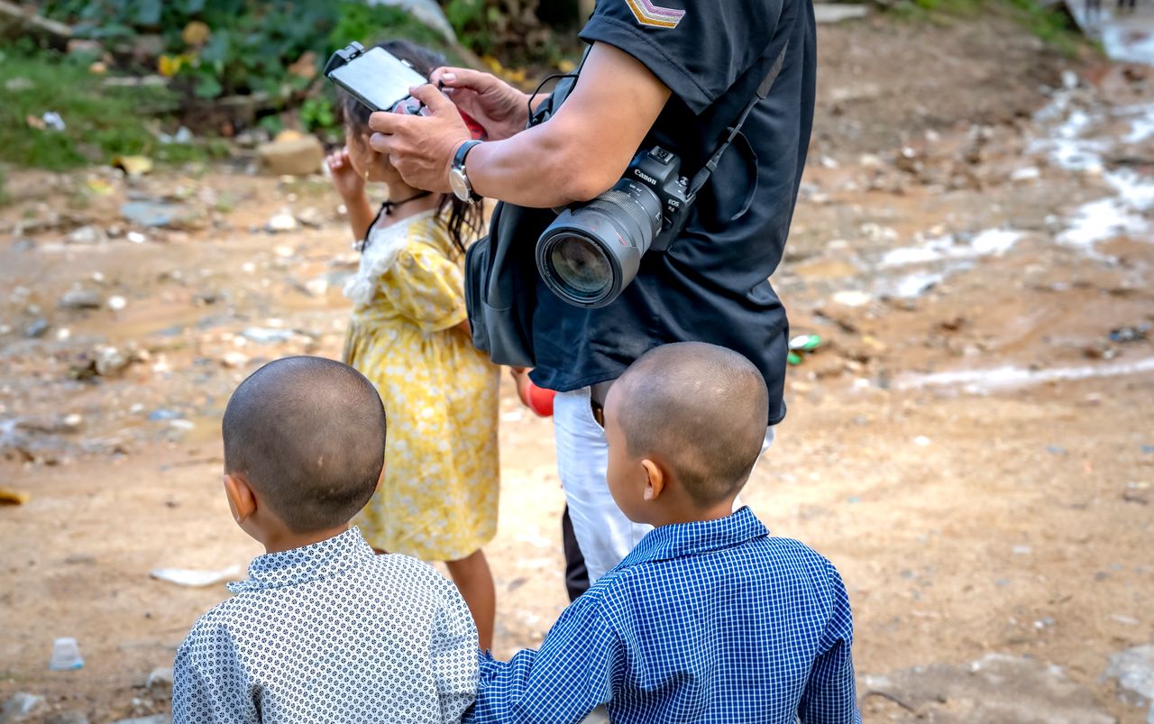 hero-img-02 Photographer capturing moments with children in a rustic outdoor scene.